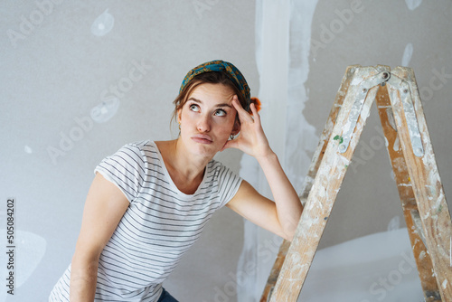 Young woman thinking how to paint the walls photo