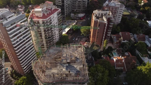 Aerial top-down orbiting over crane and roof of building under construction, Olivos city, Buenos Aires in Argentina photo