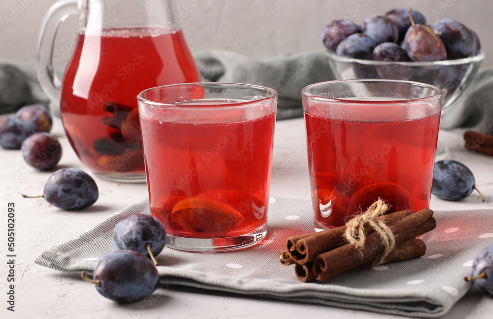 Plum Compote in jug and two glasses on light gray background Plum Compote in jug and two glasses on light gray background