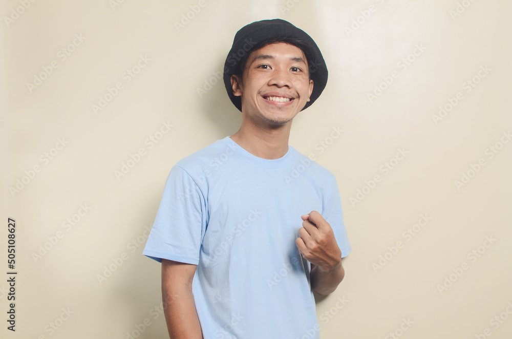Obraz premium Portrait of happy asian young man wearing blue t-shirt and black hat on isolated background