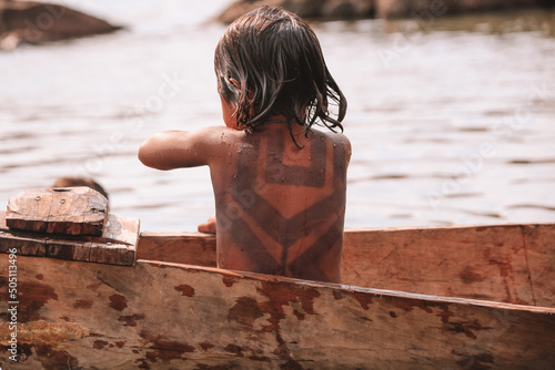 Slika na platnu Indian child from the Asurini tribe in Brazil, playing inside a canoe in the Amazon River