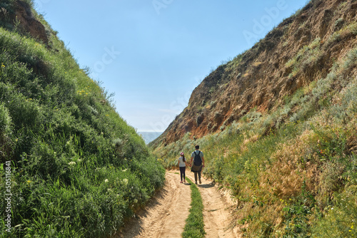 Family hikers walking in the green hills.