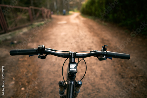Top view of mountain bike handlebar and blurred cross country forest road. Concept of extreme activity on the woods trails.