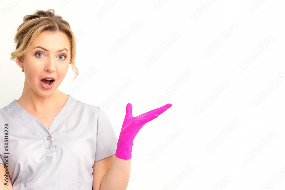 Body language. Young surprised Caucasian woman doctor wearing gloves gesturing with her hands, spread his arms having shocked expression opening her mouth against the white background Body language. Young surprised Caucasian woman doctor wearing gloves gesturing with her hands, spread his arms having shocked expression opening her mouth against the white background