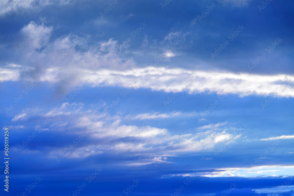 Curly clouds on a sunny day. Summer sky. Light cloudy, good weather. Beautiful bright blue background. Heaven and infinity. White clouds in the blue sky