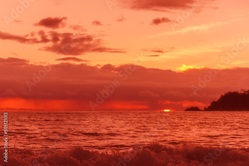 Red sun in the clouds. Colorful sunset in the evening sky. Great dramatic view. Clouds illuminated by the setting sun. Amazing sky panorama. Meditative calmness and greatness