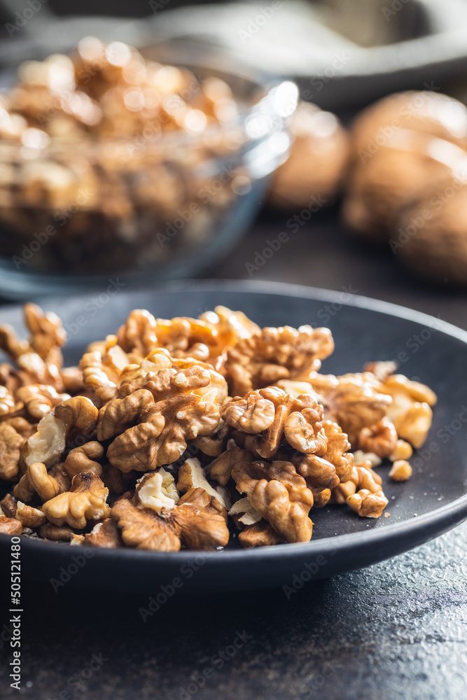 Peeled walnut kernels on plate on black table. Peeled walnut kernels on plate on black table.