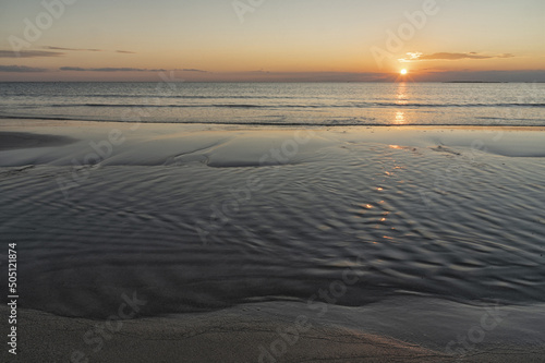 Tramonto sul mare, con riflesso del sole sull'acqua e sulla spiaggia. © vito