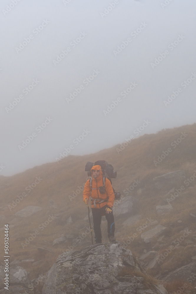 A man with a backpack for a hike climbs to the top of the mountain on a rocky path, a tourist hike in the Carpathians in Ukraine.