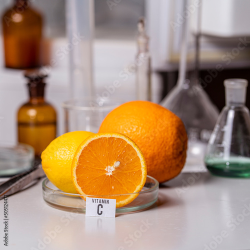 Oranges on the laboratory table with a name plate for vitamin C. Essential vitamins. Food test laboratory.