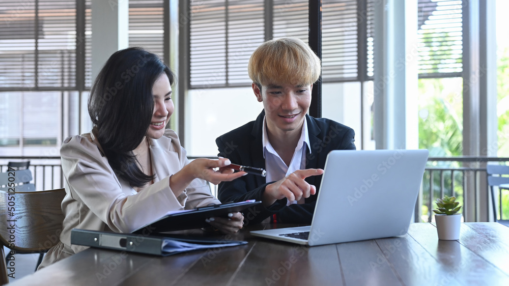 Two young businesspeople using computer laptop and discussing on new startup project together Two young businesspeople using computer laptop and discussing on new startup project together