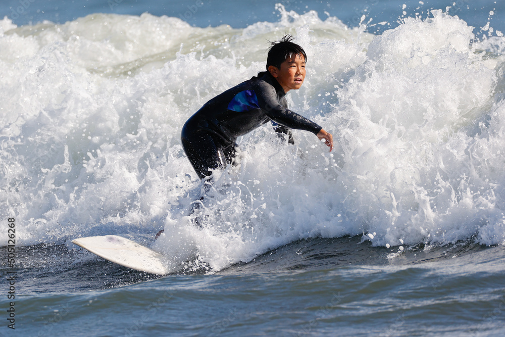 湘南の海でサーフィンをする少年