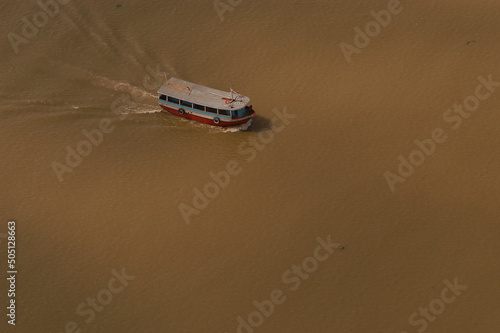 Aerial view of a boat crossing the murky waters of the Amazon River, Brazil. © Brarymi