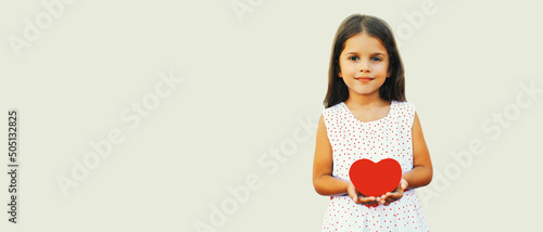 Portrait of happy child holding red paper heart on white background, blank copy space for advertising text