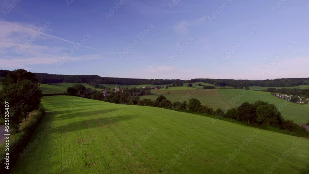 Over the rolling hills, meadows with natural fences, wooded banks, with rural roads, Beusdael Castle in the background, in South Limburg the Netherlands Aerial View Over the rolling hills, meadows with natural fences, wooded banks, with rural roads, Beusdael Castle in the background, in South Limburg the Netherlands Aerial View