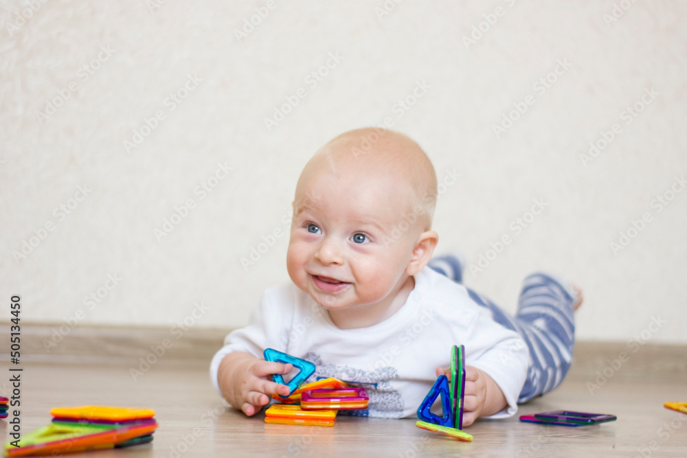 Cute infant boy with toy magnetic construction set at home. Cute infant boy with toy magnetic construction set at home.