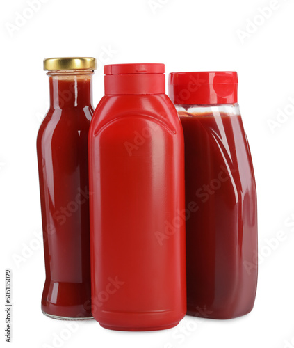 Different bottles of ketchup on white background
