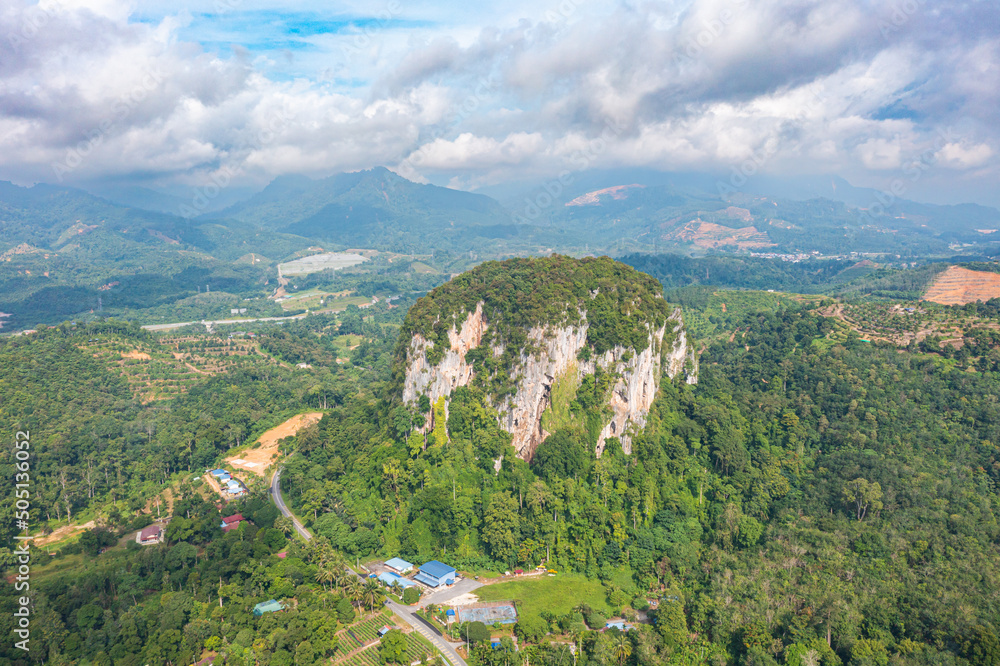 Aerial view to the Limestone hill  Bukit Batu Kapur at Cinta Manis, Pahang, Malaysia. A mountain rock out of nowhere in the middle of the Malaysian rainforest. Green overgrown with jungle vegetation.