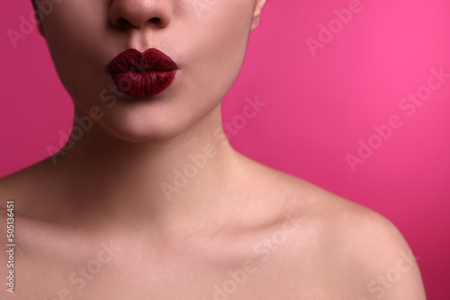 Closeup view of beautiful woman puckering lips for kiss on pink background