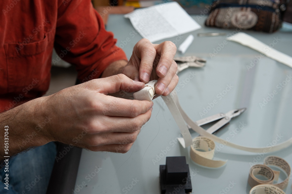 A Jewish scribe binds a scroll with Hebrew verses from the Bible before