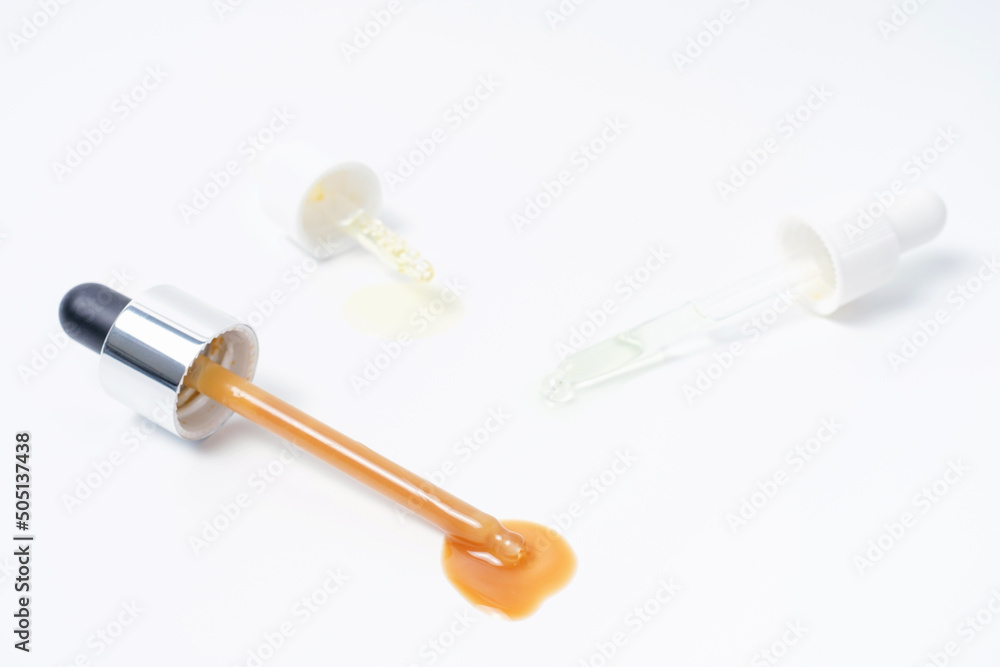 Three pipettes with serum and collagen on white background close-up. Three pipettes with serum and collagen on white background close-up.