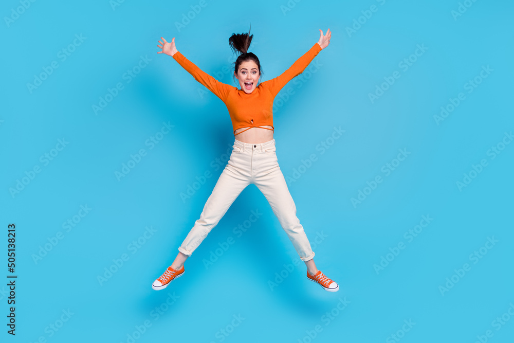 Full body image of cheerful ecstatic woman jumping star pose having fun isolated on blue color background Full body image of cheerful ecstatic woman jumping star pose having fun isolated on blue color background