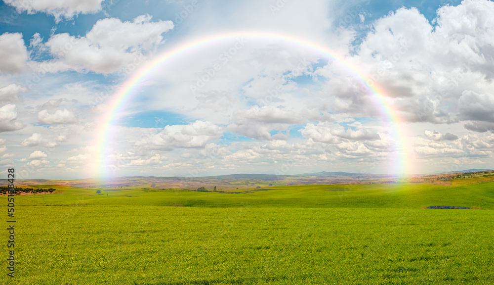 Green grass field and bright blue sky with rainbow Green grass field and bright blue sky with rainbow