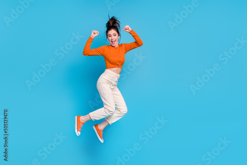 Full size image of good mood laughing girl raise fists in success triumph win lottery prize isolated on blue color background © deagreez