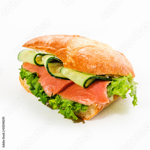 Close-up of a delicious fresh sandwich with salmon, cucumber and salad on a white background