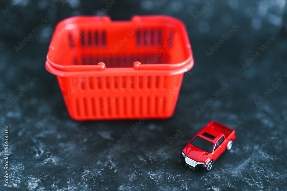 Fototapeta premium buying a new car, red toy car inside of shopping basket over black marble background
