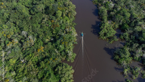 Photograph on the Amazon River of a fishing boat among the mangroves. Lush jungle. Drone photography