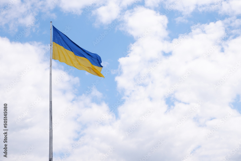 Flag of Ukraine on a high flagpole isolated on a blue sky background. Flag of Ukraine on a high flagpole isolated on a blue sky background.