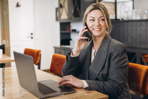 Canvas Mature business woman restaurant administrator sitting talking on the phone and