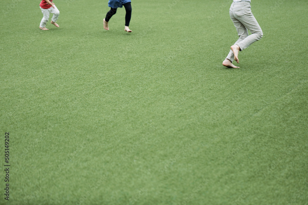 Obraz premium Legs of happy kids running in green field. Space for copy.