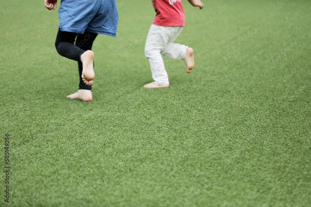 Legs of happy kids running in green field. Space for copy. Legs of happy kids running in green field. Space for copy.