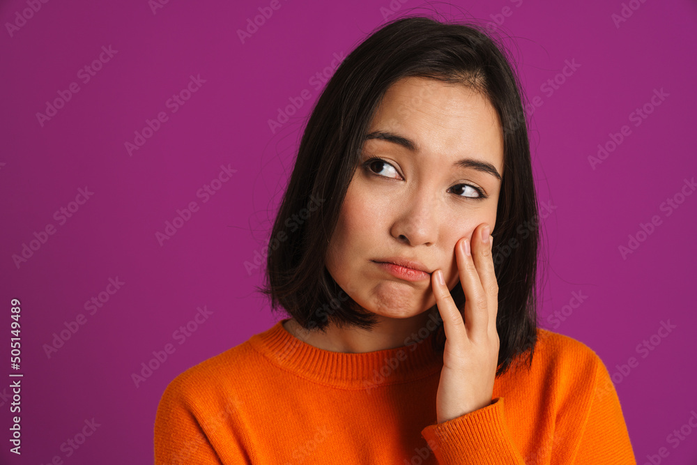 Young asian woman wearing sweater frowning and looking aside Young asian woman wearing sweater frowning and looking aside