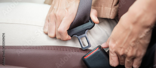 woman driver hand fastening seat belt during sitting inside a car and driving in the road. safety  trip  journey and transport concept