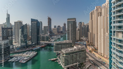 Panorama showing aerial view to Dubai marina skyscrapers around canal with floating boats timelapse