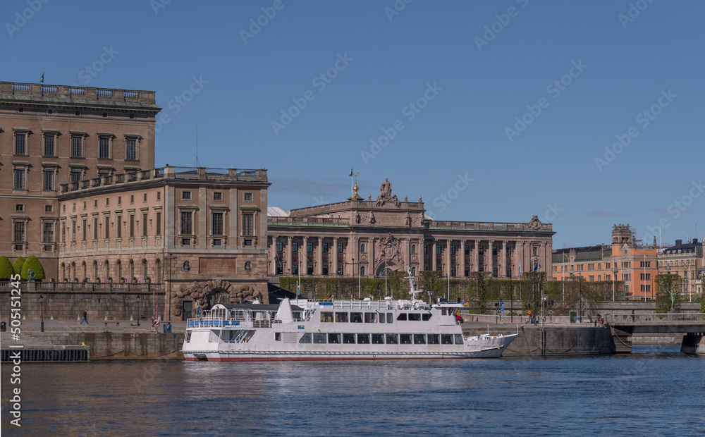 Commuting boat at the pier Strömkajen and the Swedish Parliament building on the island Helgeandsholmen a sunny day in Stockholm
