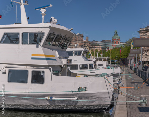 Commuting boats at the pier Strömkajen and the church Jakobs kyrka a sunny day in Stockholm