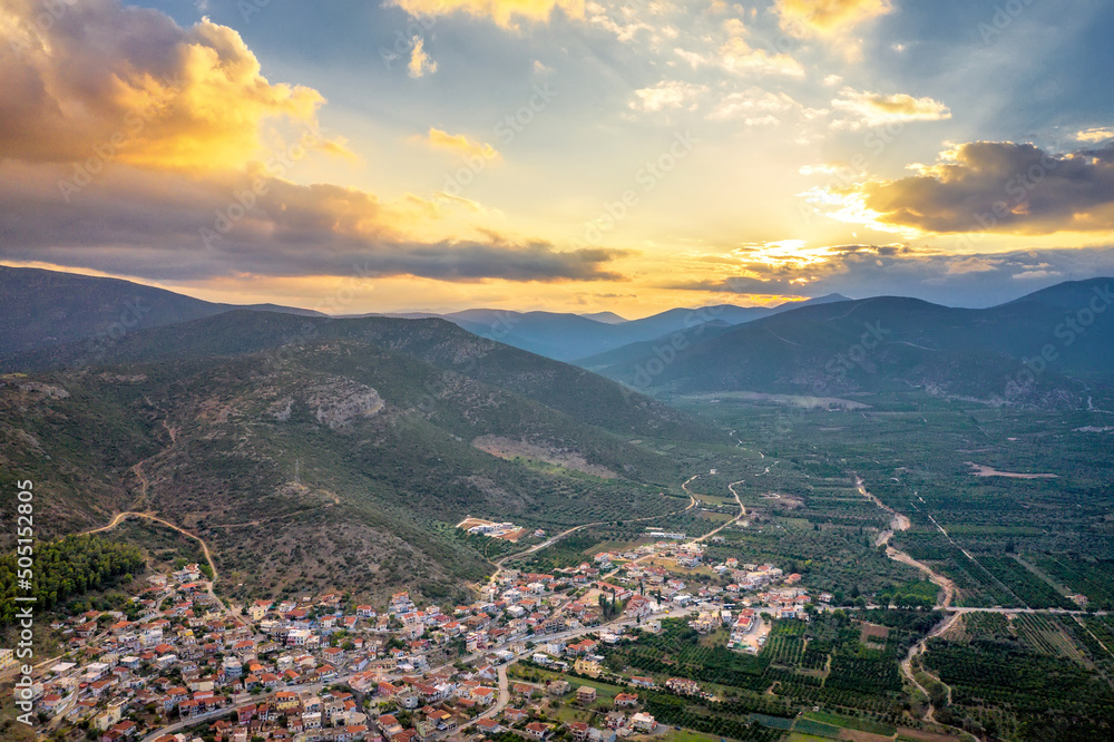Aerial view of a small Greek village on the coast of the Mediterranean sea. Green hills of Peloponnese peninsula, Greece, Europe. Travel to Greece landscape