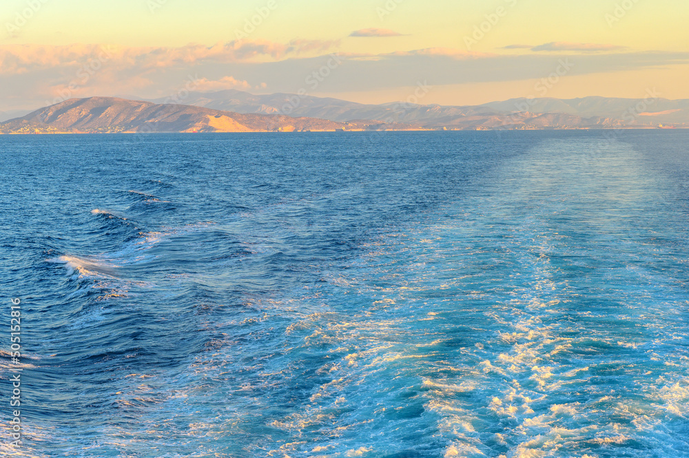 View of the wake water trace behind a ferry at sea at sunrise or sunset..