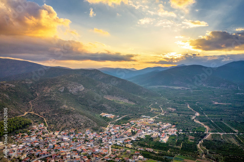 Aerial view of a small Greek village on the coast of the Mediterranean sea. Green hills of Peloponnese peninsula, Greece, Europe. Travel to Greece landscape