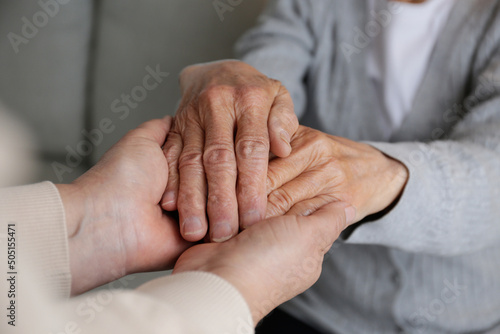 Fototapeta Naklejka Na Ścianę i Meble -  Mature female in elderly care facility gets help from hospital personnel nurse. Cropped shot of senior woman's hands with aged wrinkled skin and care giver. Background, copy space, close up.