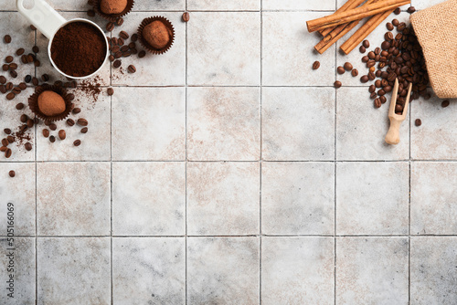 Coffee background. Measuring spoons with ground coffee, beans, cup and sweet chocolate truffles on old tile cracked table background. Food background. Top view with space for your text