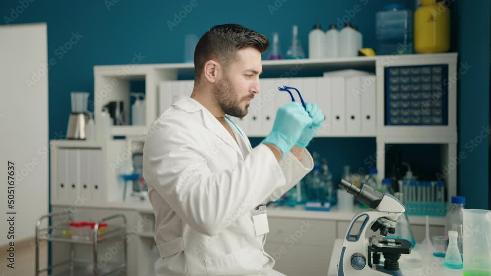 Young hispanic man wearing scientist uniform and glasses at laboratory Young hispanic man wearing scientist uniform and glasses at laboratory