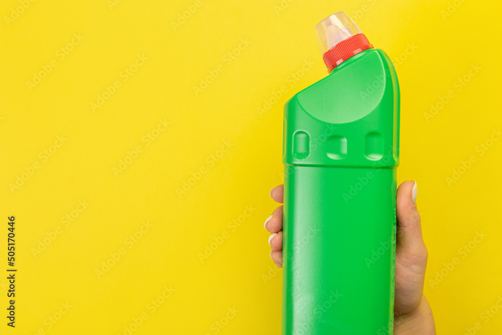 Cleaner's hand holding a  chemical spray bottle. Empty space for text or logo on a yellow background. Early spring or regular cleaning. Cleaning and cleaning concept. flat lay