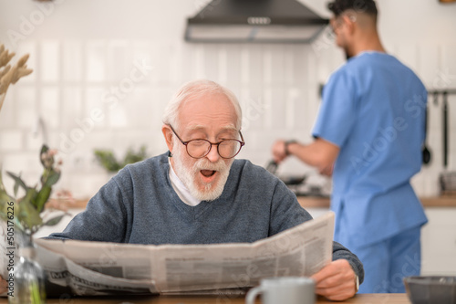 Male pensioner reading news before the morning meal