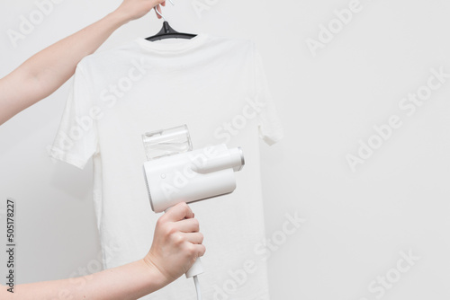 hand-held clothes steamer with white T-shirt on a light background