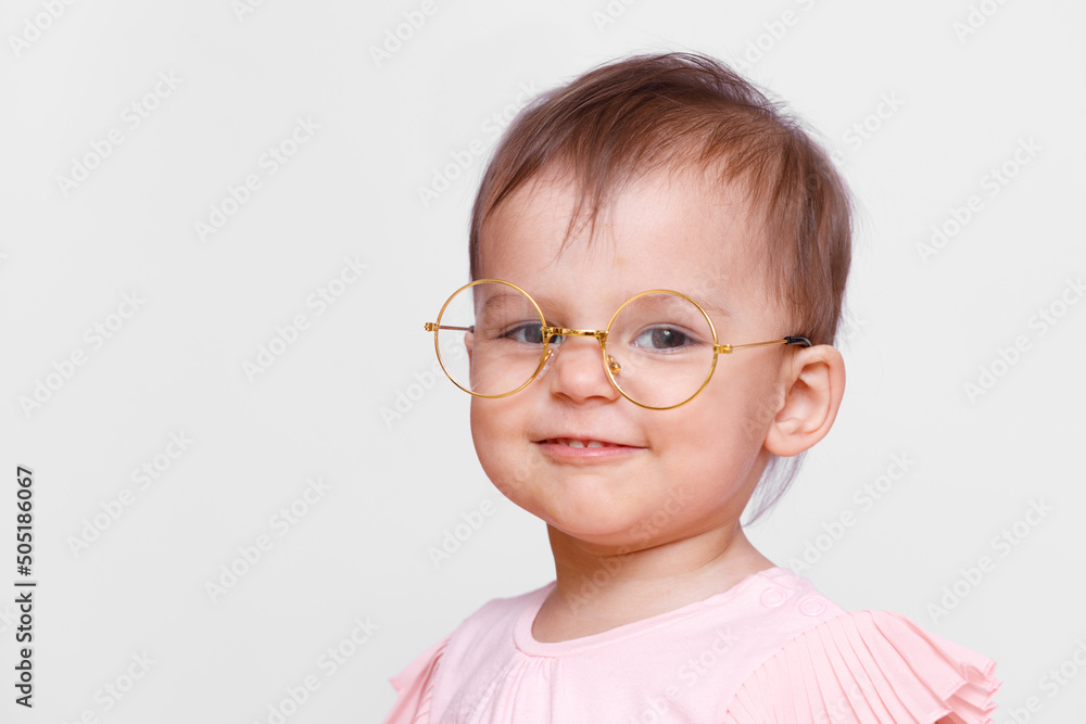 Portrait of smart toddler girl. Little pretty girl in glasses. Gray background. Free space for text.